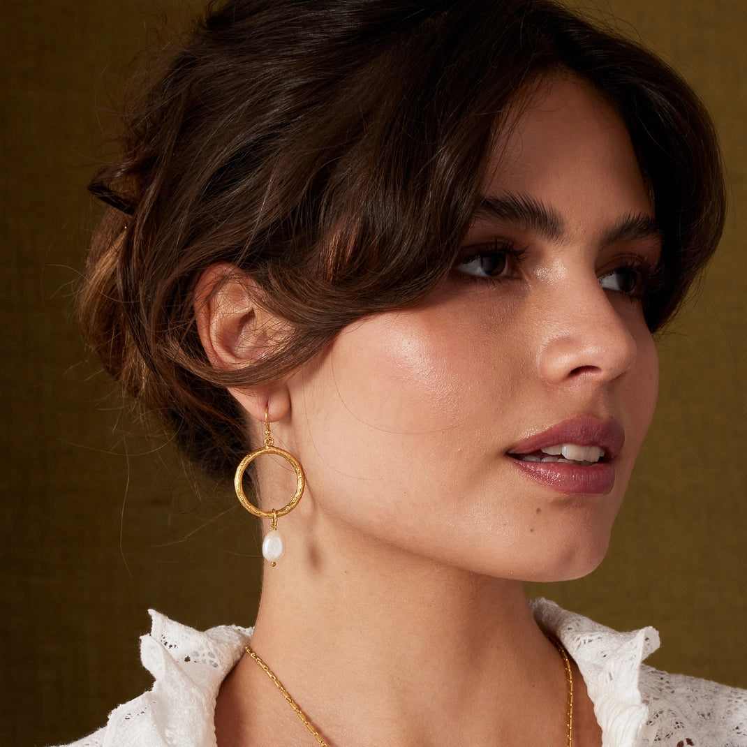 Gold hoop earrings with pearl drops on a white background