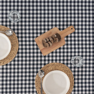 Table setting with bread on a wooden board over a navy and white checkered tablecloth.