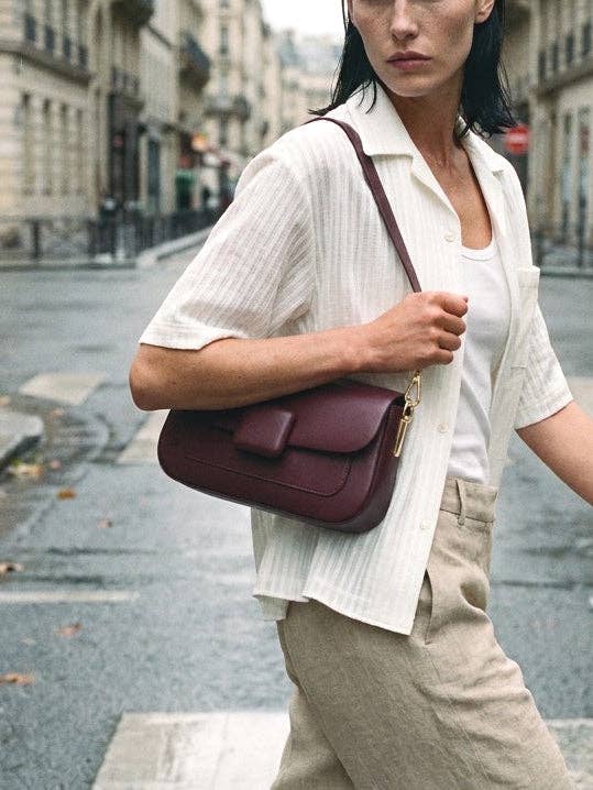 Woman holding a maroon handbag on a city street