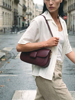 Woman holding a maroon handbag on a city street