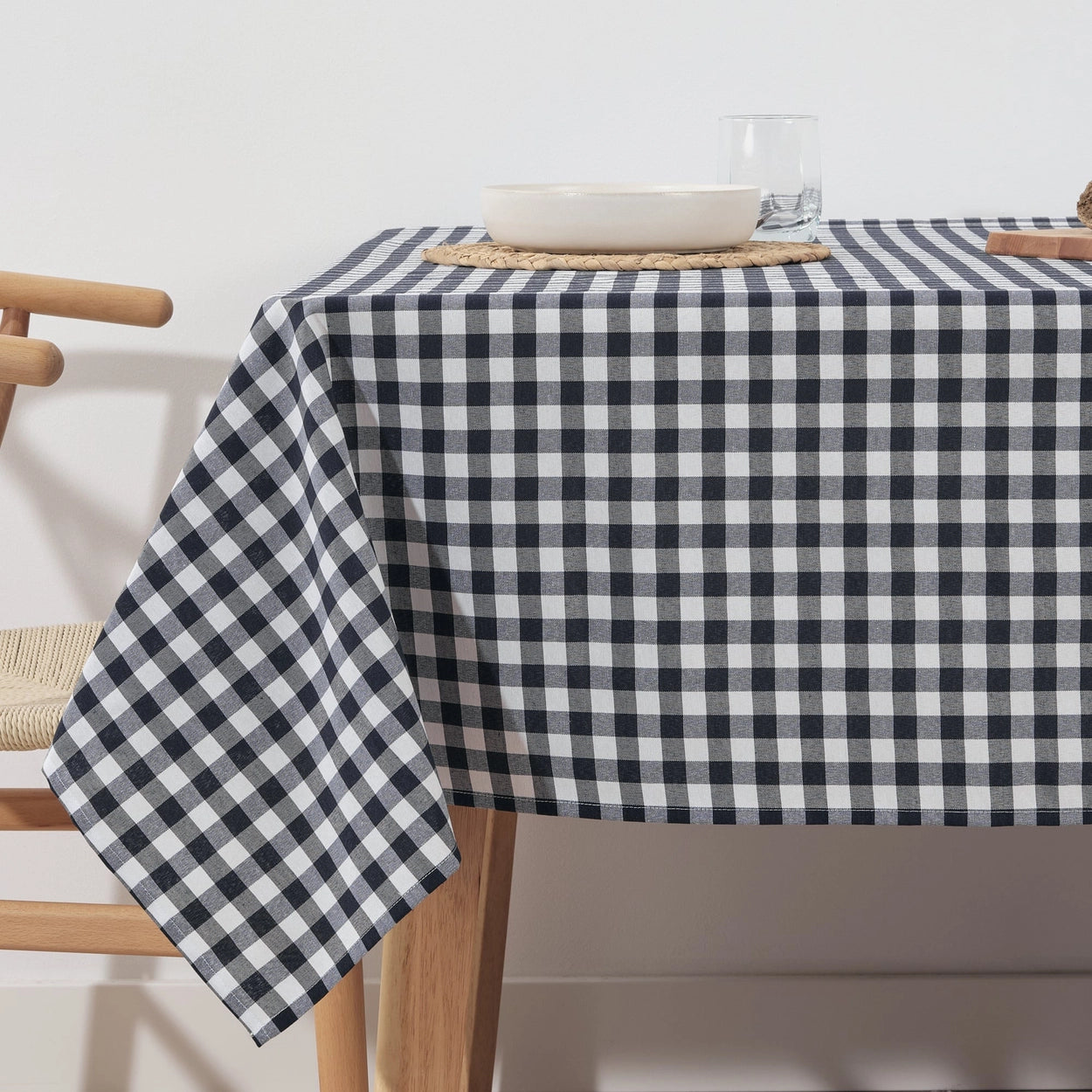 Table with a navy and white checkered tablecloth, wooden chairs, and minimal decor.