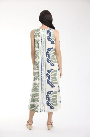 A woman viewed from the back wearing a sleeveless midi dress with a vertical floral print in blue, green, and beige on a white base, paired with beige wedge sandals, against a plain white studio background.