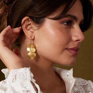 Woman wearing gold earrings with a blurred background