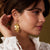 Woman wearing gold earrings with a blurred background
