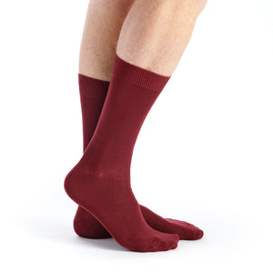 A pair of crew socks in a deep burgundy red color, worn on a person's legs against a plain white background.