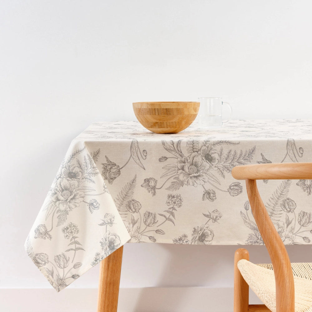 Floral-patterned tablecloth on a wooden table with a bowl and chair.