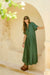 Woman in a green dress standing in an archway with floral decorations.