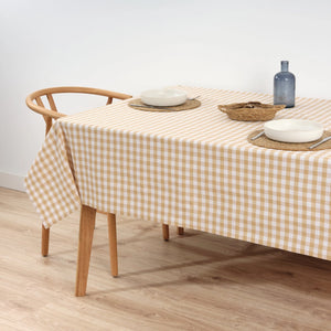 Dining table with a checkered tablecloth, plates, and a bottle on a wooden floor.