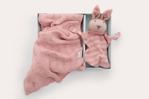 Pink baby blanket and toy on a white background