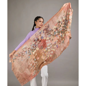 Woman holding a large abstract patterned scarf against a plain background