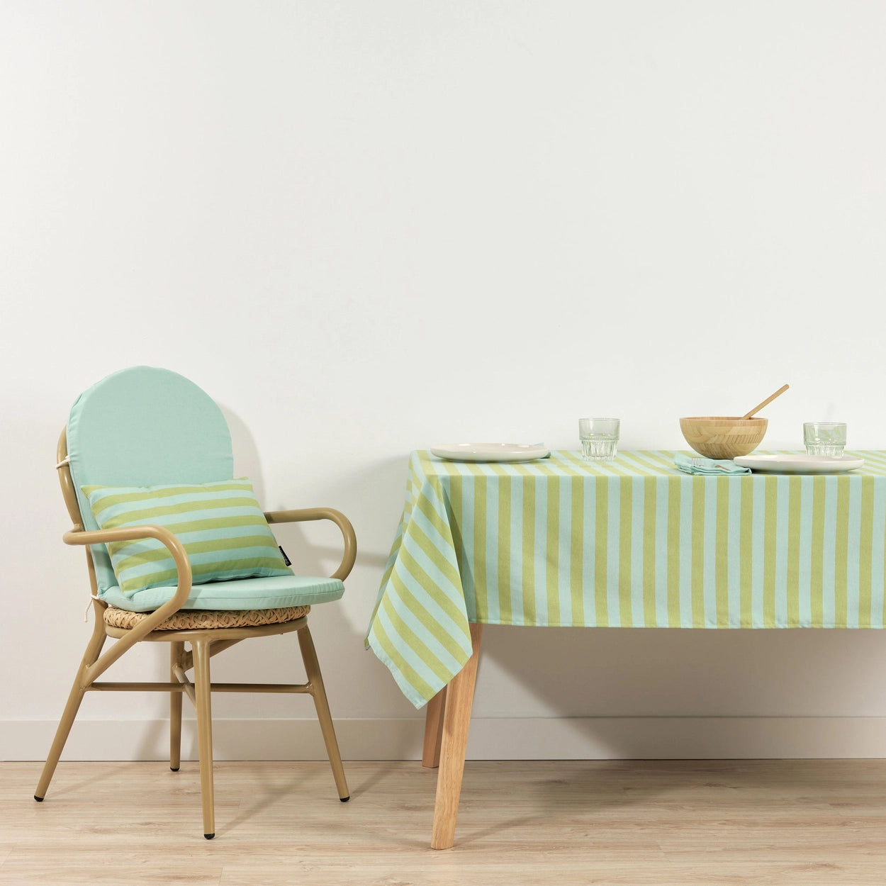 Chair with striped cushion next to a table with a matching green and aqua striped tablecloth.