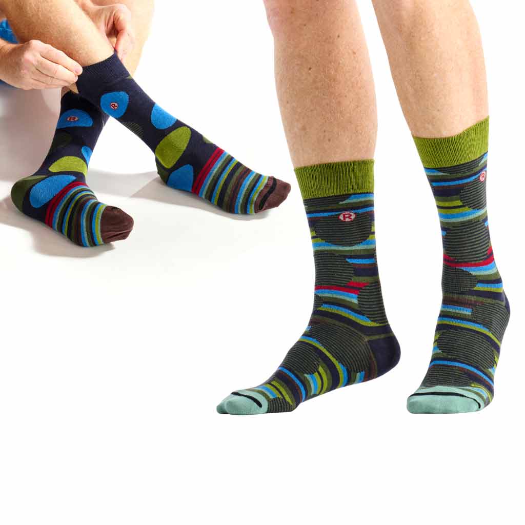 Multicolor striped crew socks shown on a model's feet and hands adjusting the socks on the other leg, against a clean white background.