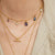 Close-up of a person wearing multiple gold necklaces with various pendants.