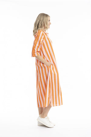 A woman modeling a loose, mid-calf length striped shirt dress in orange and white vertical stripes, paired with white sneakers, shown from a side profile against a plain white background.