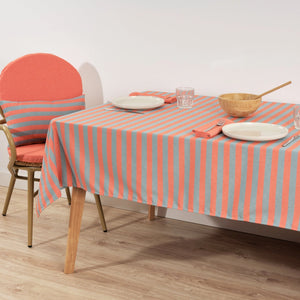 Dining table with striped tablecloth, plates, and chairs in a room.