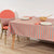 Dining table with striped tablecloth, plates, and chairs in a room.