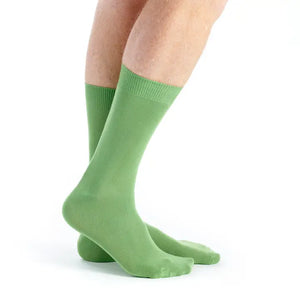 A pair of solid light green crew socks worn on a person's feet, shown from the calf down against a clean white background.