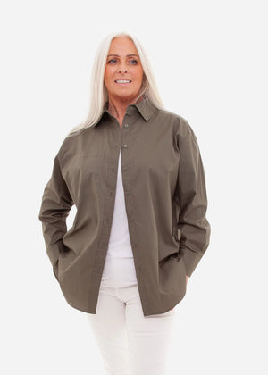 Woman wearing a khaki button-up shirt over a white top on a white background