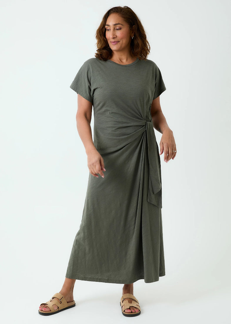 Woman wearing a green dress with a knot detail on a white background