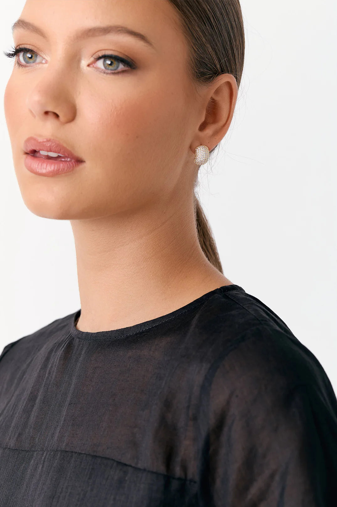 Pair of gold glittery earrings on a light gray background