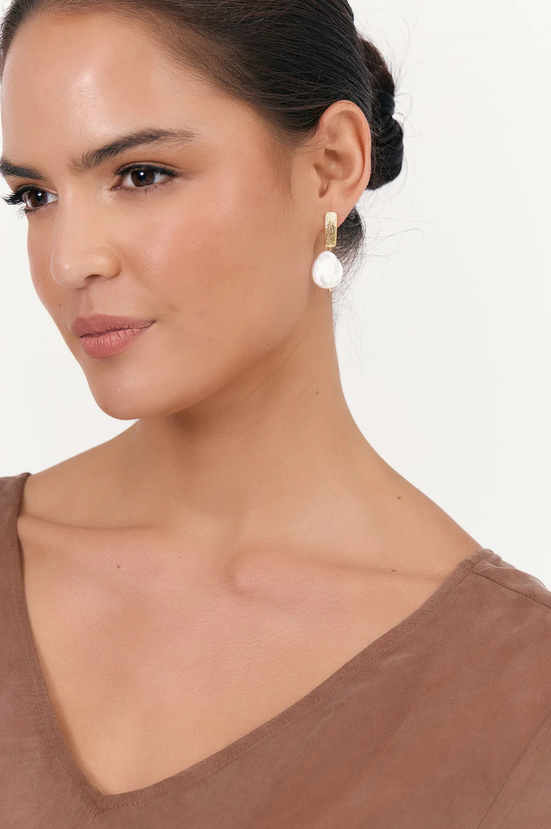 Gold earrings with pearl-like stones on a white background