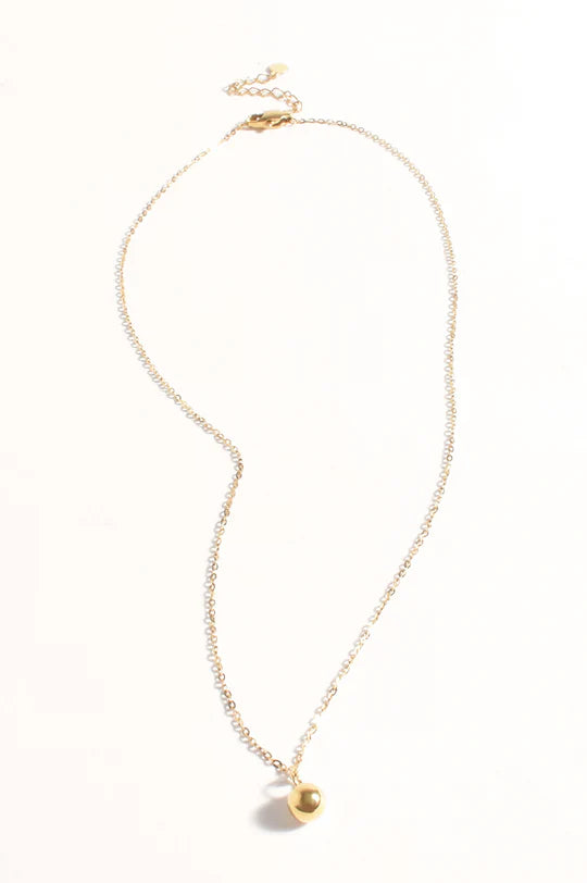 Woman wearing a delicate gold necklace against a plain background