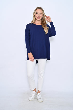 Woman wearing a navy blue sweater and white pants on a white background
