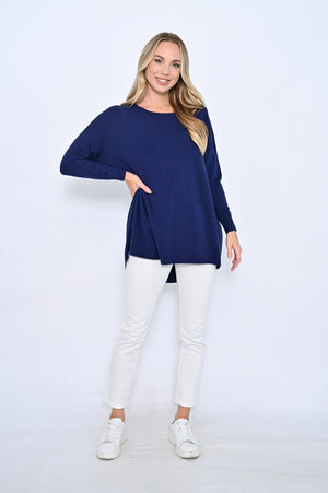Woman wearing a navy blue sweater and white pants on a white background