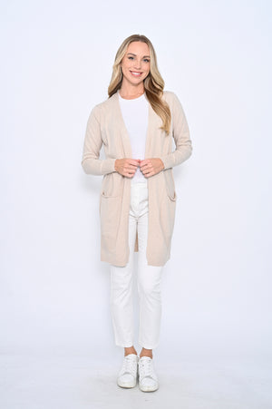 Woman wearing a beige cardigan over a white top and pants on a white background