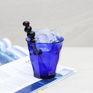 Blue glass with ice and berries on a white surface