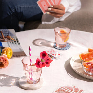 Table setting with drinks, snacks, and playing cards on a white surface.
