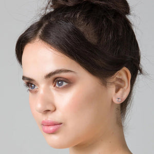 Woman with styled hair against a gray background wearing stud earrings