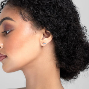 Woman with styled hair wearing earrings against a neutral background