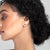 Woman with styled hair wearing earrings against a neutral background