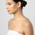 Woman with a stylish hair bun wearing a white strapless top against a plain background