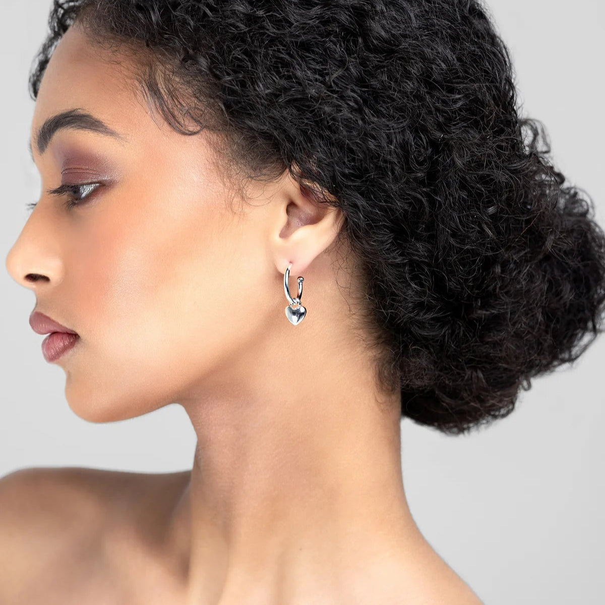 Gold hoop earrings with heart pendants on a white background