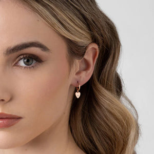 Close-up of a woman wearing a heart-shaped earring against a white background