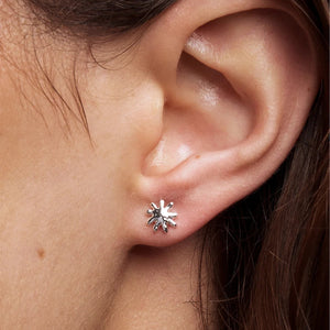 Close-up of an ear wearing a silver sun-shaped earring.