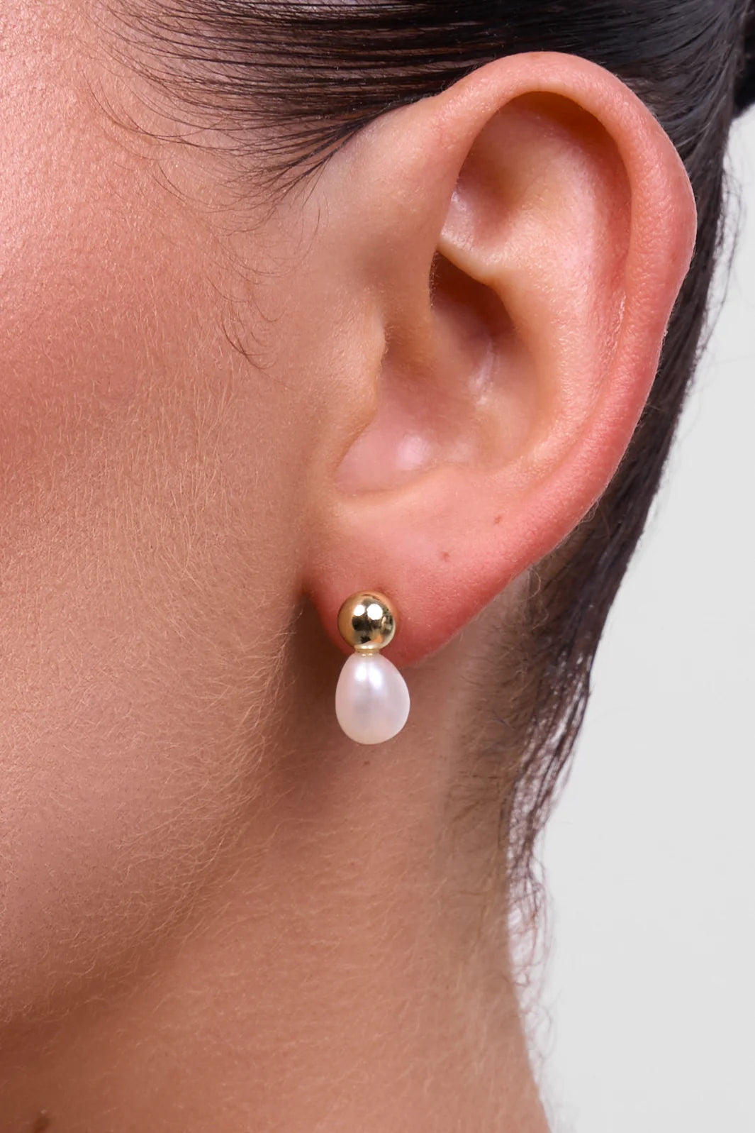 Pair of earrings with gold and white spherical designs on a white background
