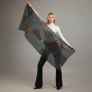 Woman holding a patterned scarf against a plain background