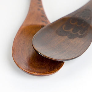 Two dark brown wooden spoons with engraved patterns, shown in a close-up product shot against a clean white background.