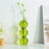 Colorful glass vases with stems on a light surface