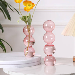 Pink glass vase with floral arrangement on a white surface