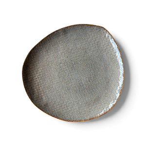 An organic-shaped ceramic plate with a textured, woven-like glaze in gray and blue tones, finished with a rustic brown rim, shown from a top-down perspective on a white background.