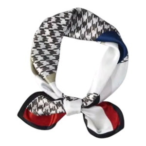 A square silk scarf with a black and white houndstooth pattern, featuring solid white, navy blue, and red borders, tied in a knot on a white background.