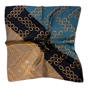 A square silk scarf with a geometric chain-link pattern, featuring diagonal sections of black, teal blue, and beige, all decorated with gold interlocking rings, shown on a plain white background.