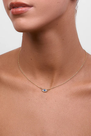Gold necklace with a small pendant on a person's neck against a neutral background