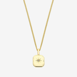 Gold necklace with a square pendant on a light gray background