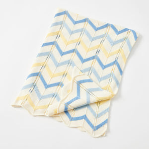 Folded baby blanket with blue and yellow chevron pattern on a light gray background