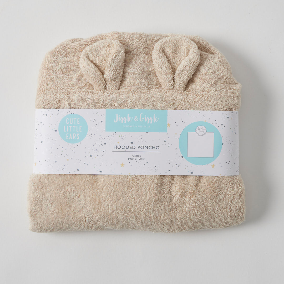 Child wearing a beige hooded towel standing in a bathroom with a freestanding bathtub.